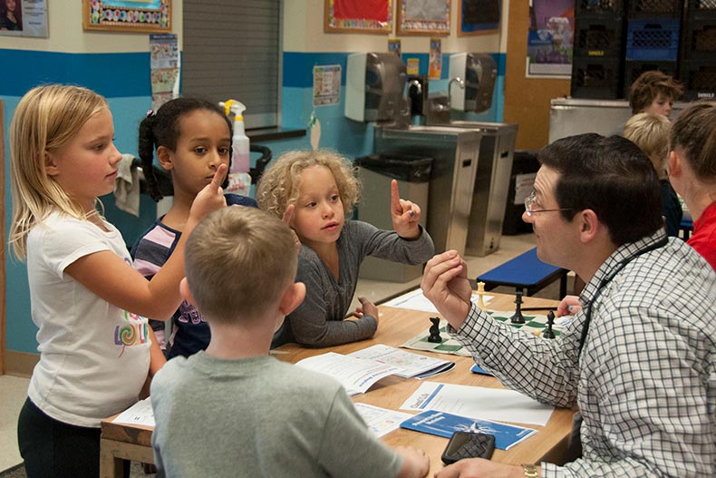 Elliott Neff teaching Boys & Girls Club children how to play chess- Fall 2016. Photo by Sarah Smoots